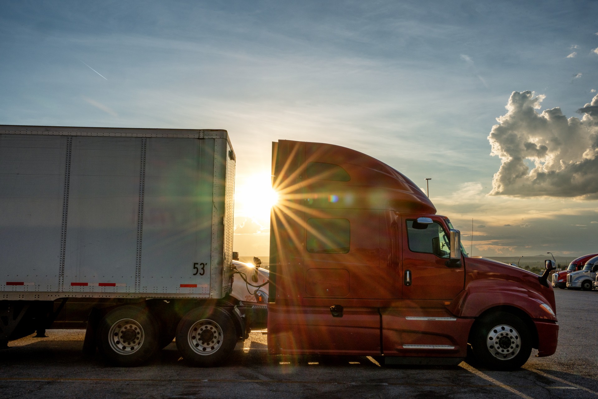 Red Colored Semi-Truck Speeding on a Two-Lane Highway with Cars in Background Under a Stunning Sunset in the American Southwest